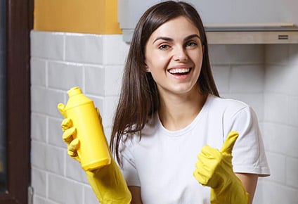 Tevreden schoonmaakster met schoonmaakmiddel